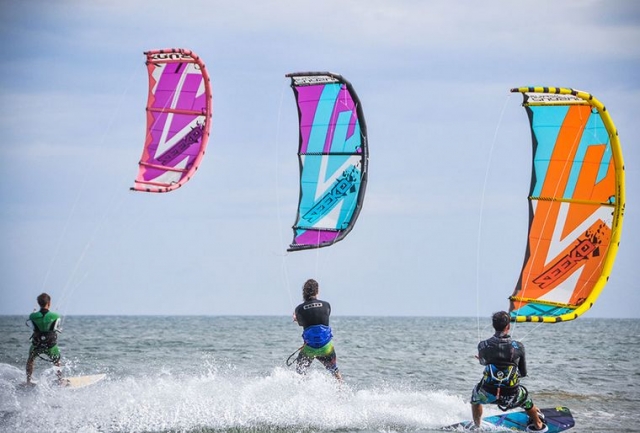 Chicos volando sus cometas mientras practican kitesurf
